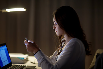 Image showing businesswoman with smartphone at night office