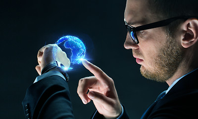 Image showing businessman with smart watch and earth hologram