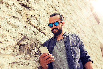 Image showing man texting message on smartphone at stone wall