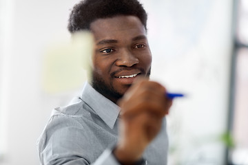 Image showing businessman writing on glass board at office