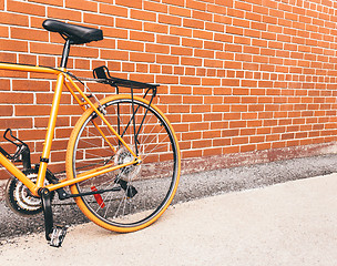 Image showing Orange bicycle near red brick wall with copy space