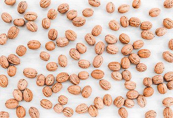 Image showing Lots of walnuts scattered on white wooden background