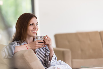 Image showing young woman in a bathrobe enjoying morning coffee