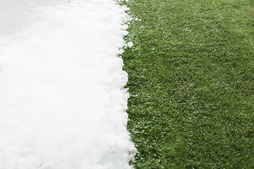 Image showing Meeting snow on green grass close up - between winter and spring concept background