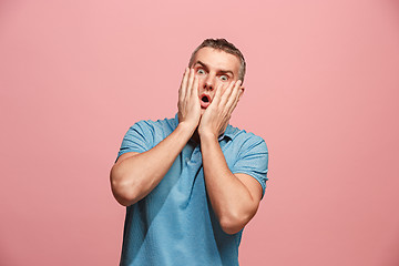 Image showing The young attractive man looking suprised isolated on pink