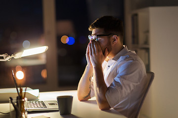 Image showing tired businessman with laptop at night office