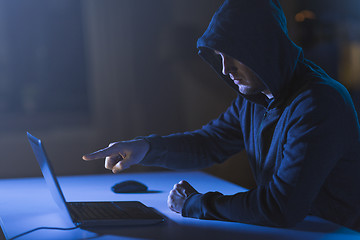 Image showing hacker pointing at laptop computer in dark room