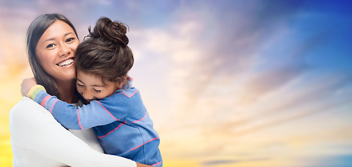 Image showing happy mother and daughter hugging over evening sky