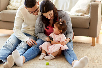 Image showing little girl with smartphone and parents at home