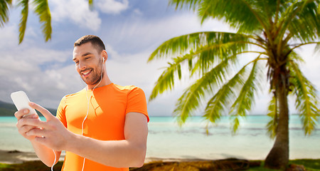 Image showing man with smartphone and earphones over beach