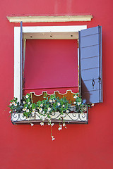 Image showing Window on a red wall, decorated with flowers