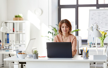 Image showing happy businesswoman with laptop working at office