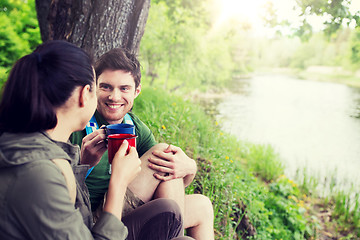 Image showing happy couple with cups drinking in nature