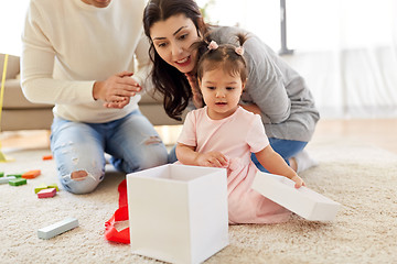 Image showing baby girl with birthday gift and parents at home