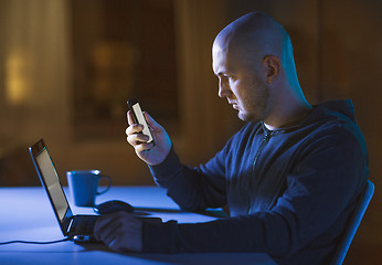 Image showing hacker with laptop and smartphone in dark room