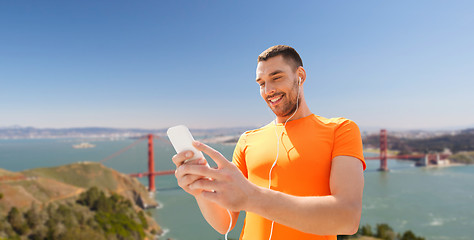 Image showing man with smartphone and earphones over golden gate