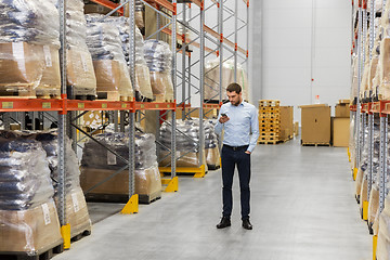 Image showing businessman with smartphone at warehouse