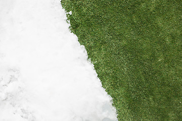 Image showing Meeting snow on green grass close up - between winter and spring concept background