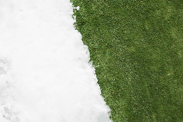 Image showing Meeting snow on green grass close up - between winter and spring concept background