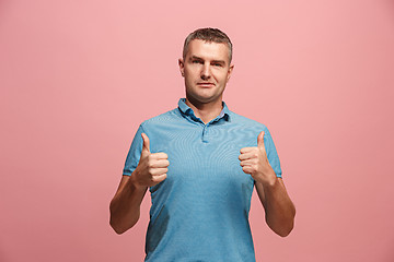 Image showing The happy businessman standing and smiling against pink background.