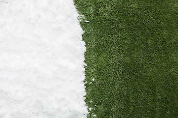 Image showing Meeting snow on green grass close up - between winter and spring concept background