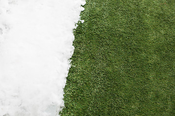 Image showing Meeting snow on green grass close up - between winter and spring concept background