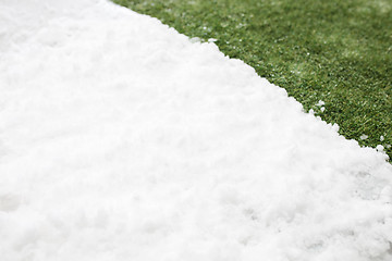 Image showing Meeting snow on green grass close up - between winter and spring concept background