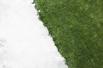 Image showing Meeting snow on green grass close up - between winter and spring concept background