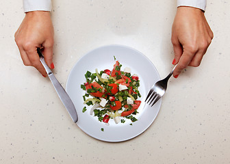 Image showing salad for visitor which holds knife and fork