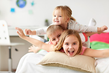 Image showing happy little kids having fun in bed at home