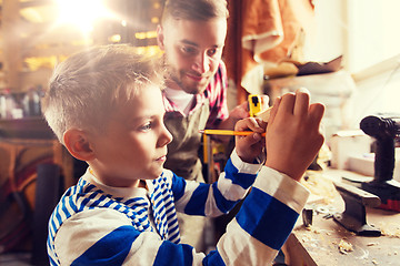 Image showing father and son with ruler measure wood at workshop