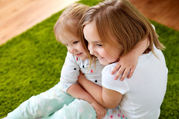 Image showing happy little girls or sisters hugging at home