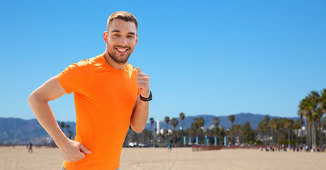 Image showing smiling young man running at summer seaside