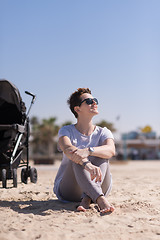 Image showing Young mother with sunglasses relaxing on beach