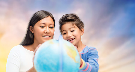 Image showing happy mother and daughter with globe over sky