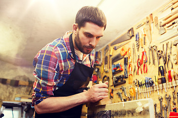 Image showing carpenter working with plane and wood at workshop