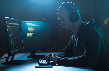 Image showing hacker with coding on laptop computer in dark room