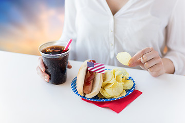 Image showing close up of woman eating hot dog with cola