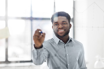 Image showing businessman writing on glass board at office