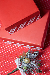 Image showing Christmas gift boxes and twig of Christmas tree on a red wrappin