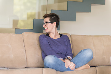 Image showing portrait of a young beautiful woman sitting on the sofa