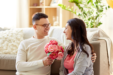Image showing happy husband giving flowers to his wife at home
