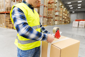 Image showing warehouse worker packing parcel with scotch tape