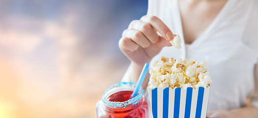 Image showing woman eating popcorn with drink in glass mason jar