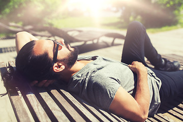 Image showing happy man lying on street bench or sun bed 