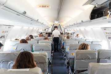 Image showing Interior of commercial airplane with passengers on their seats during flight.