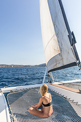 Image showing Woman relaxing on a summer sailing cruise, sitting on a luxury catamaran near picture perfect Palau town, Sardinia, Italy.