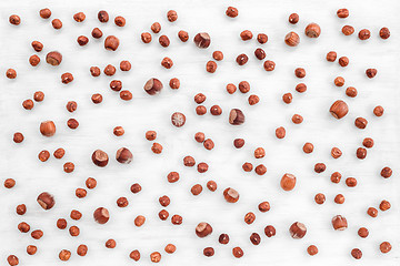 Image showing Peeled and shelled hazelnuts on white wooden background