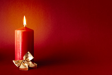 Image showing Christmas decoration with a burning candle on red background