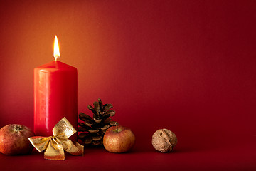 Image showing Christmas decoration with a burning candle on red background